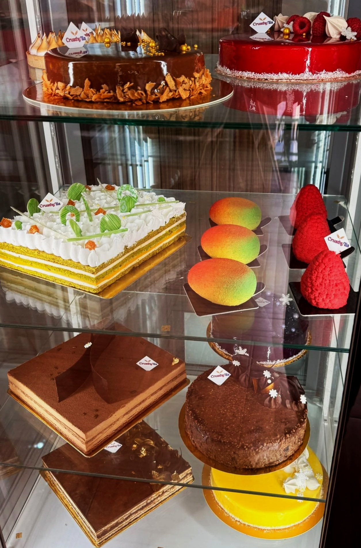 Vitrine à pâtisseries avec plusieurs gâteaux colorés et décorés.