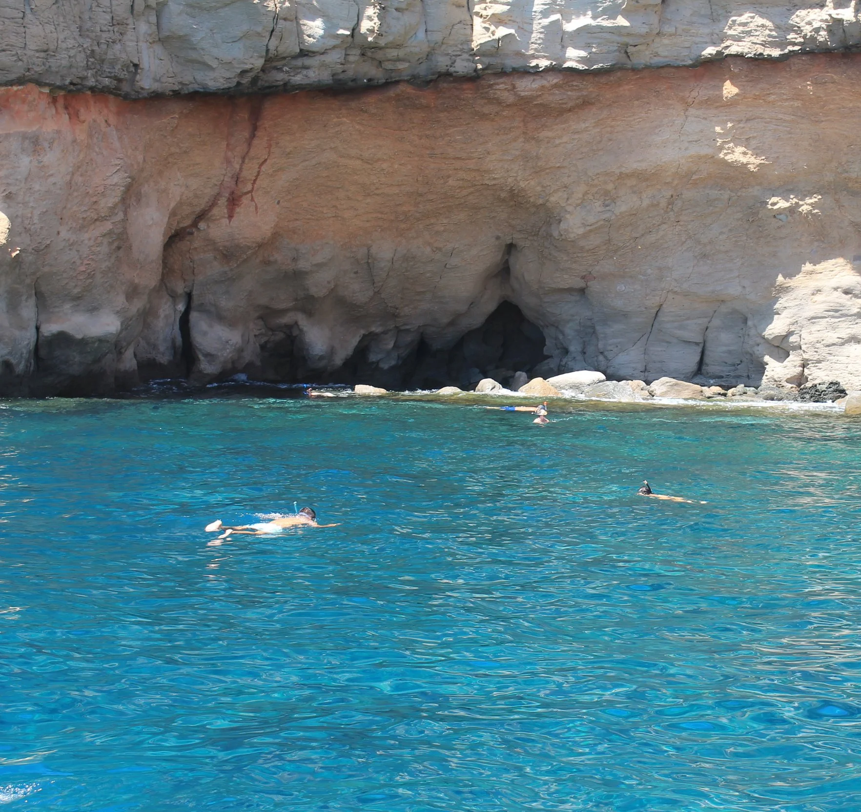 People snorkelling in clear blue waters.