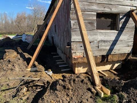 Under construction of a wooden shed or house with support beams and exposed soil