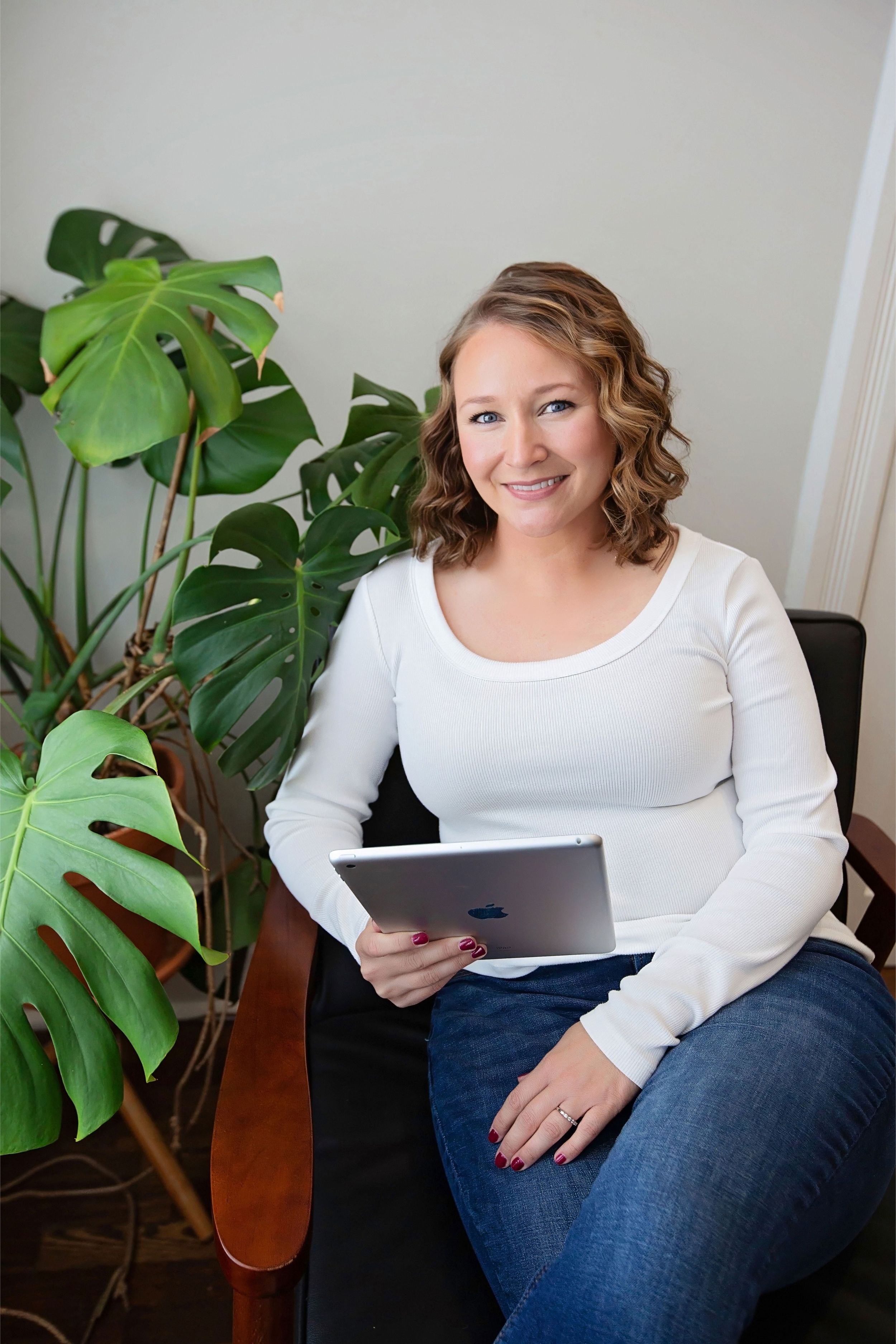 Certified bookkeeper for creators sitting in a chair with an iPad, helping clients stay organized and tax-ready