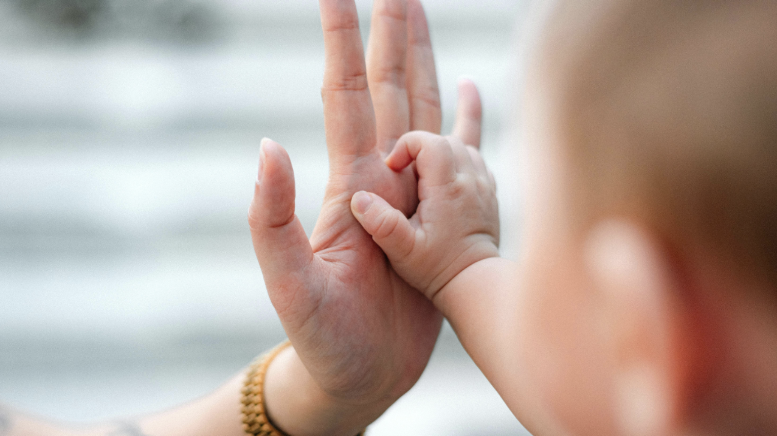 Close-up of two hands performing the 'okay' gesture, with one hand's fingers touching the thumb to form a circle and the other hand's fingers extended upward.