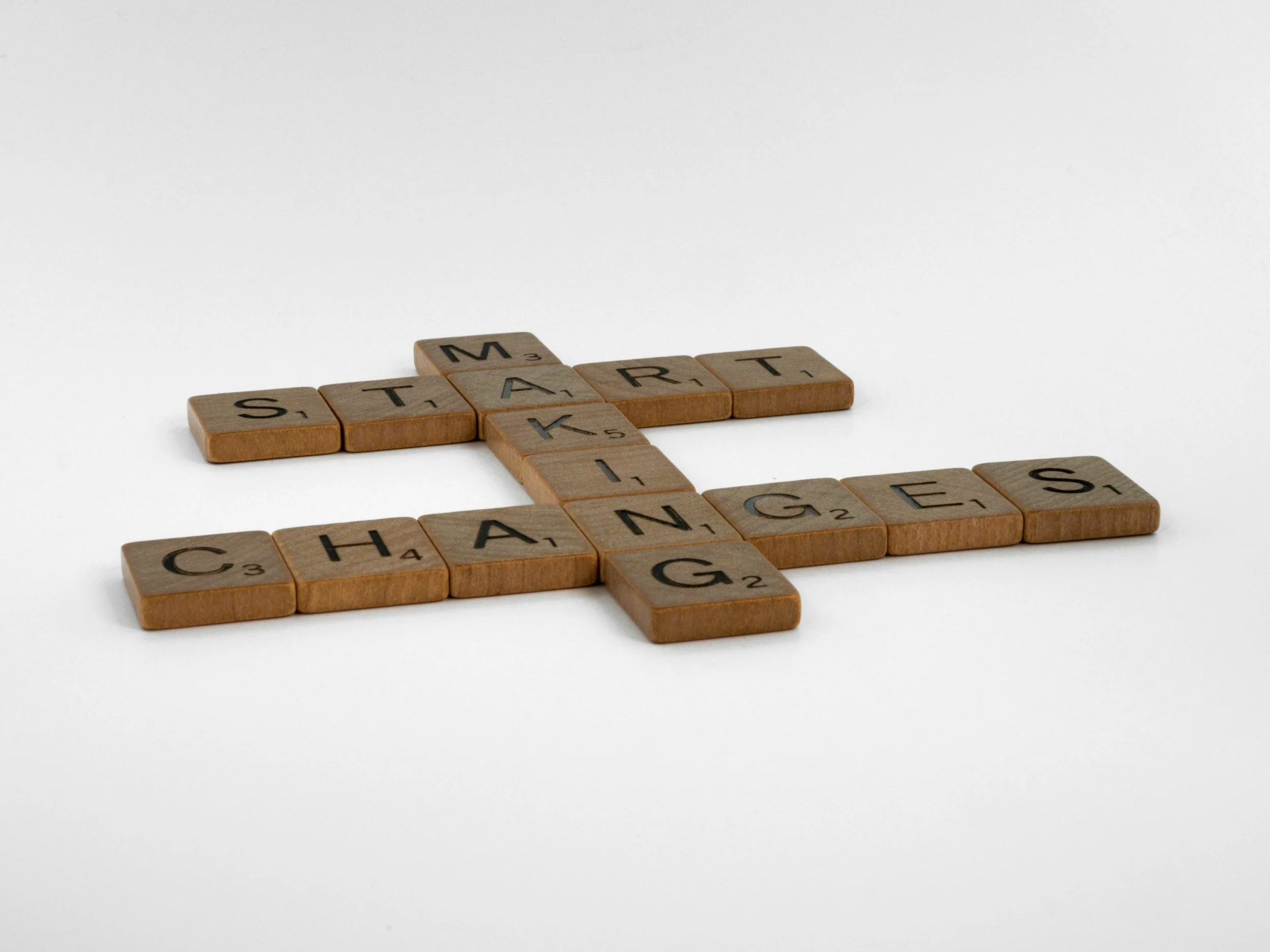 Scrabble tiles spelling out 'START', 'CHANGE', and 'GAMES' arranged on a white surface.