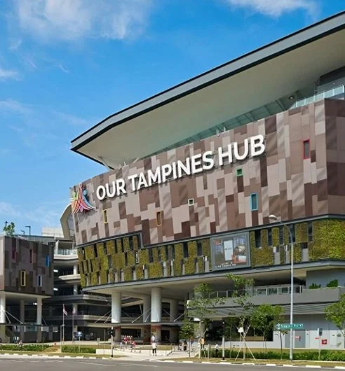 Exterior view of Our Tampines Hub, a community and sports complex in Tampines, Singapore, with modern architecture and signage.