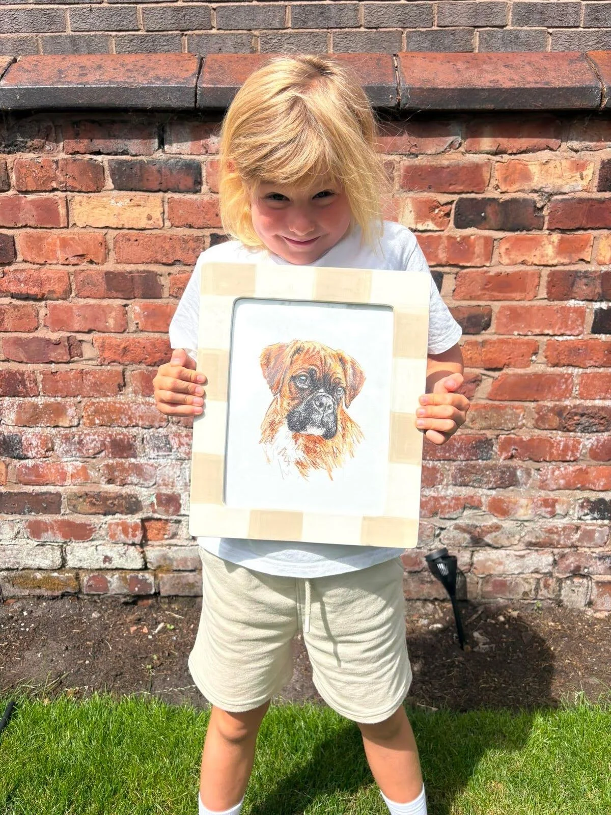 Mabel holding her hand drawn pet portrait of boxer dog