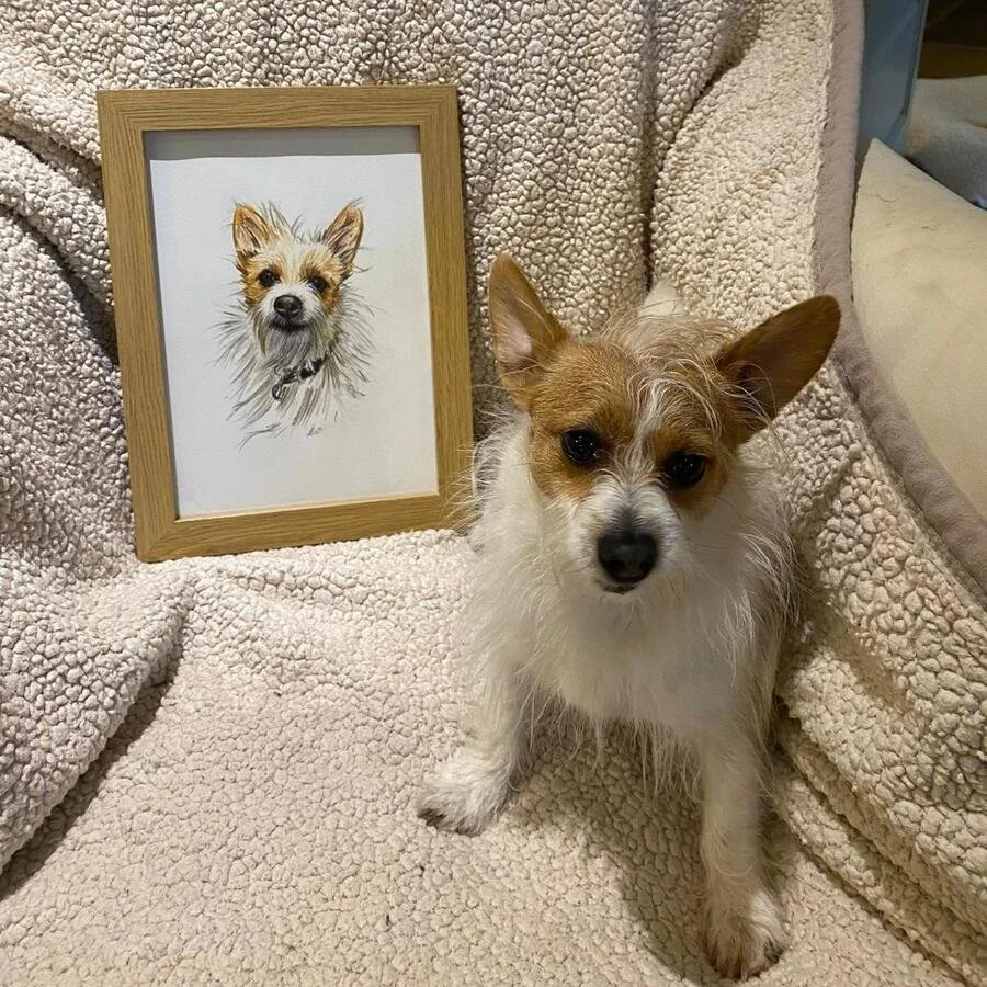 Pebbles the dog next to her hand-drawn pet portrait