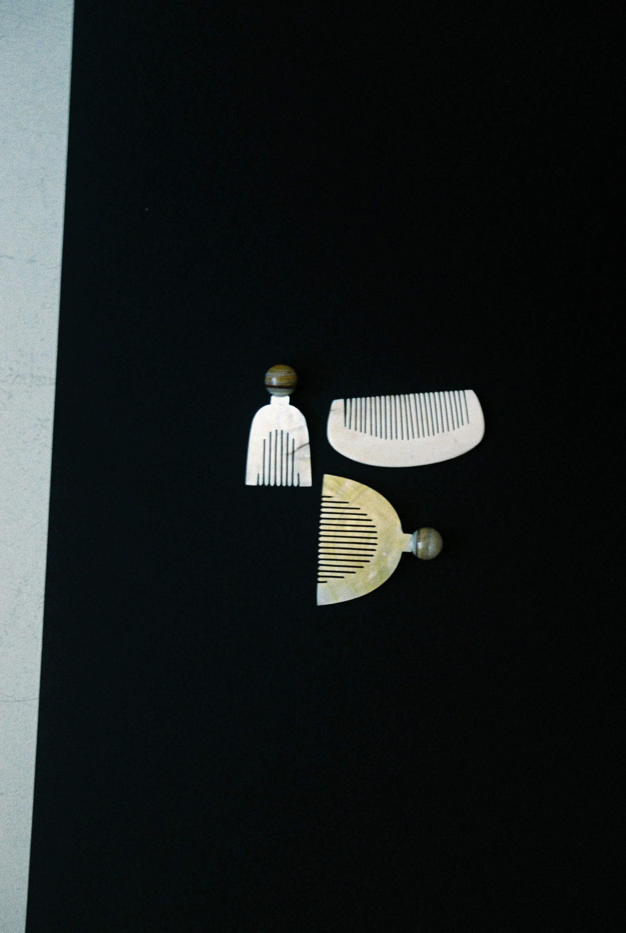 Photo of a decorative haircombs, in bone and horn, set against a black background.