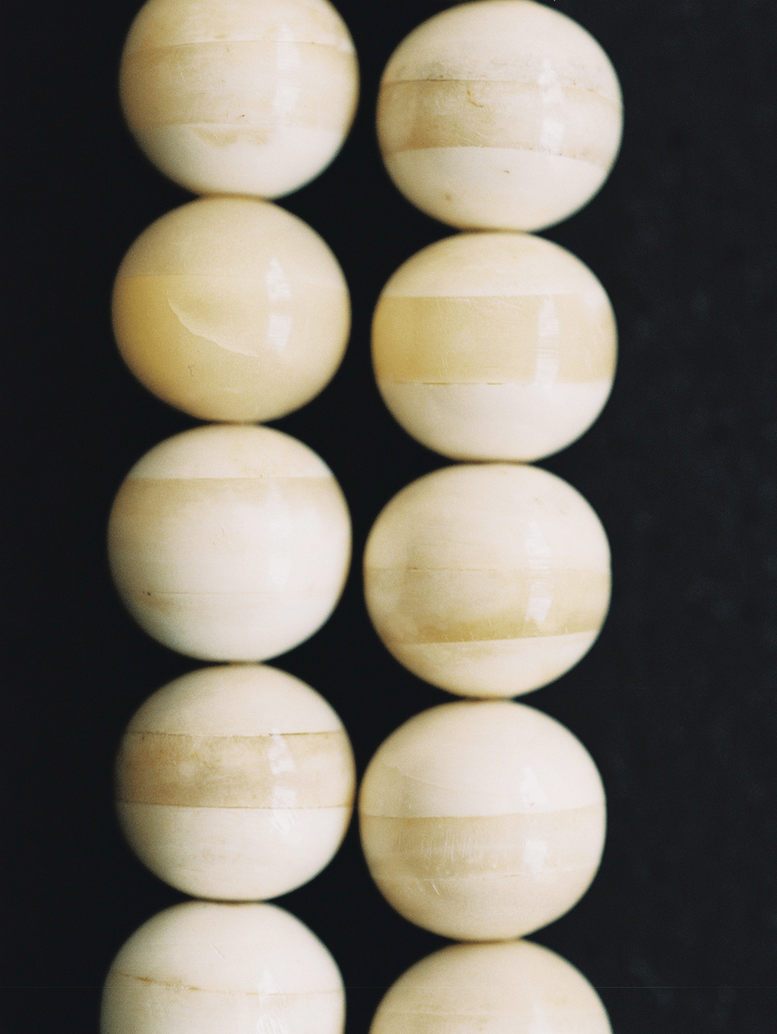 Close-up view of a bone mala bead necklace on a black surface.