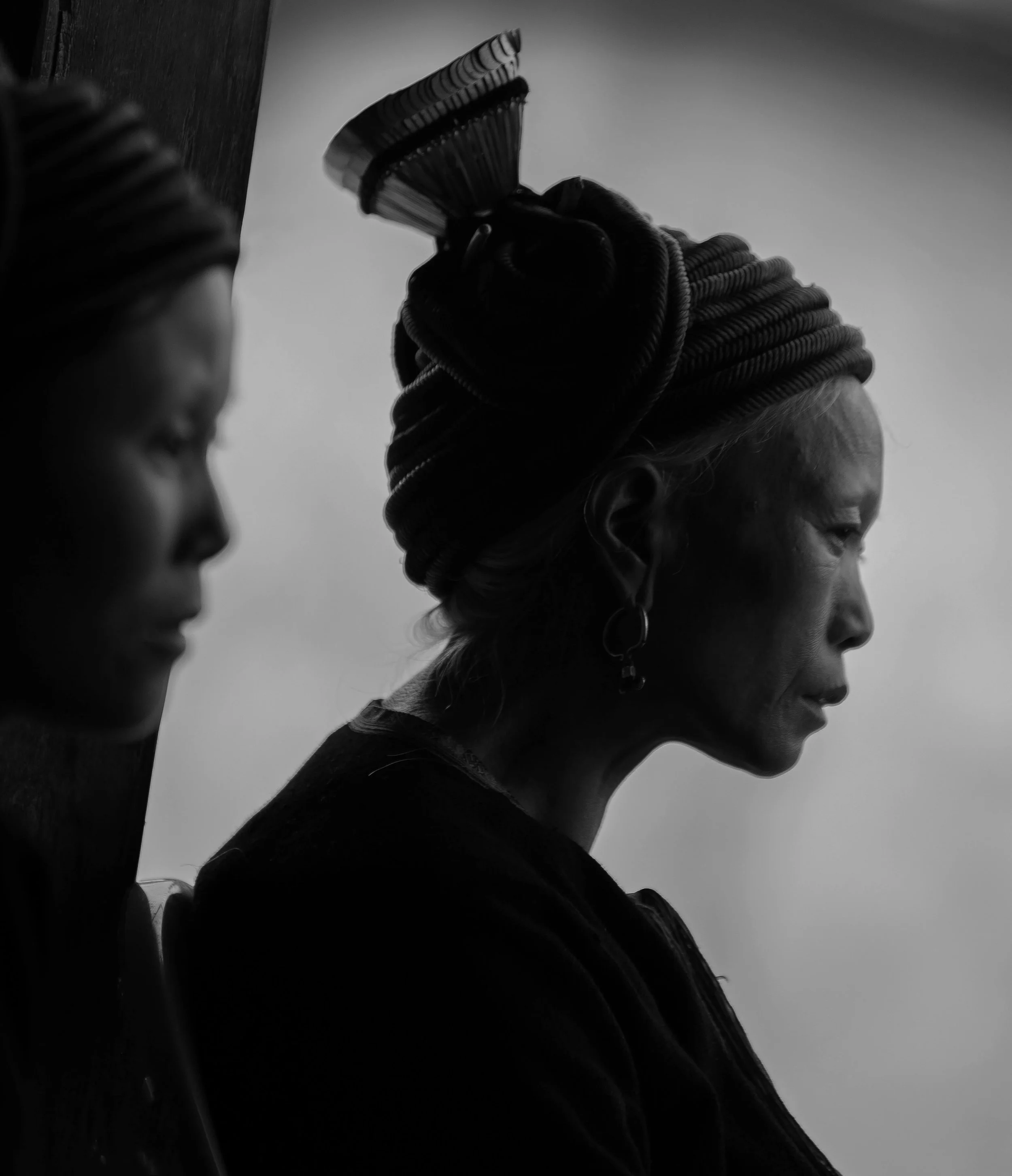 A black-and-white photograph of two Vietnamese people. The image is taken from a side profile, with the background in soft focus.