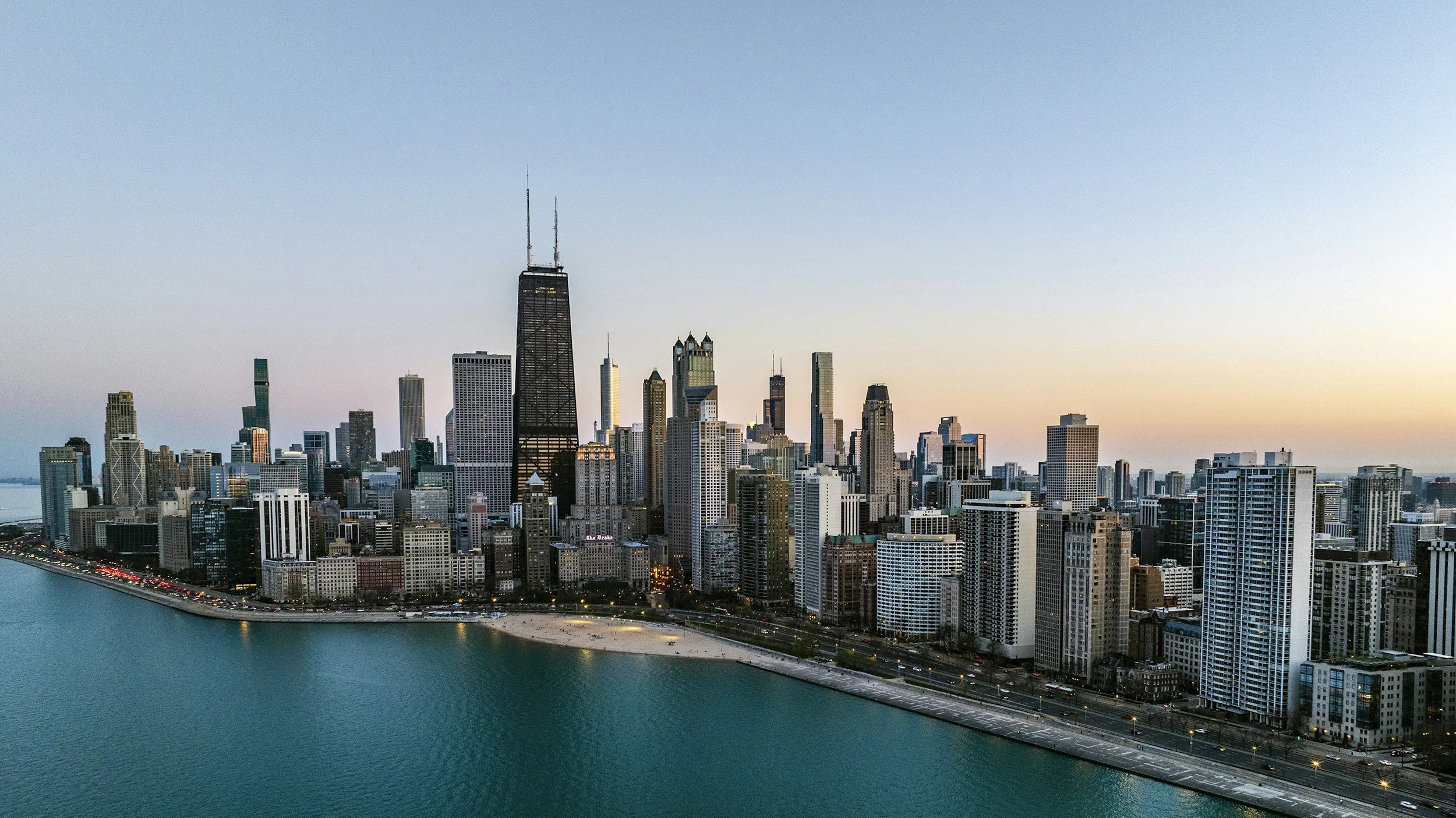 Chicago skyline at dusk with numerous skyscrapers along Lake Michigan.