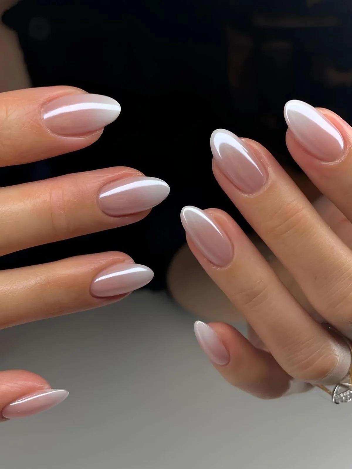 Close-up of manicured fingernails with a glossy, ombré French tip design in neutral shades of pink and white.