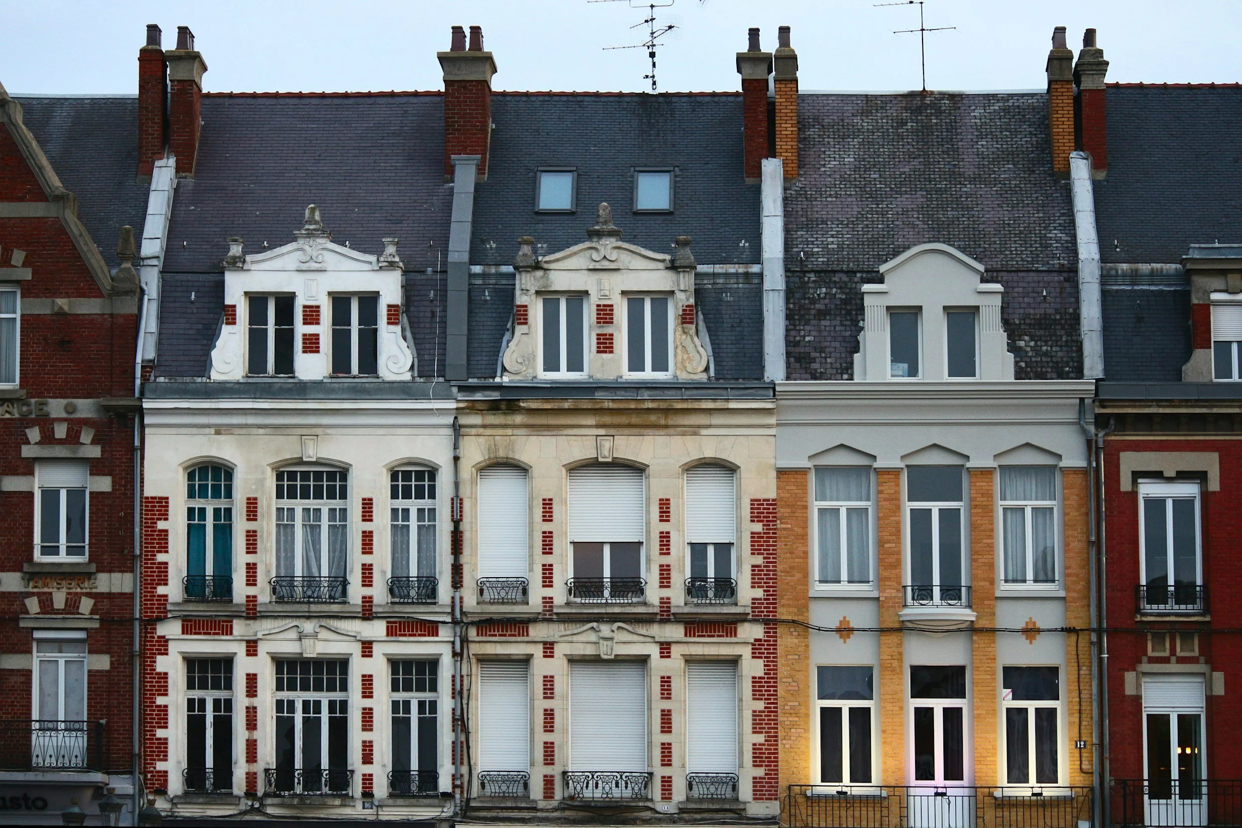 Façade de bâtiments résidentiels anciens avec fenêtres, balcons et toits en ardoise.