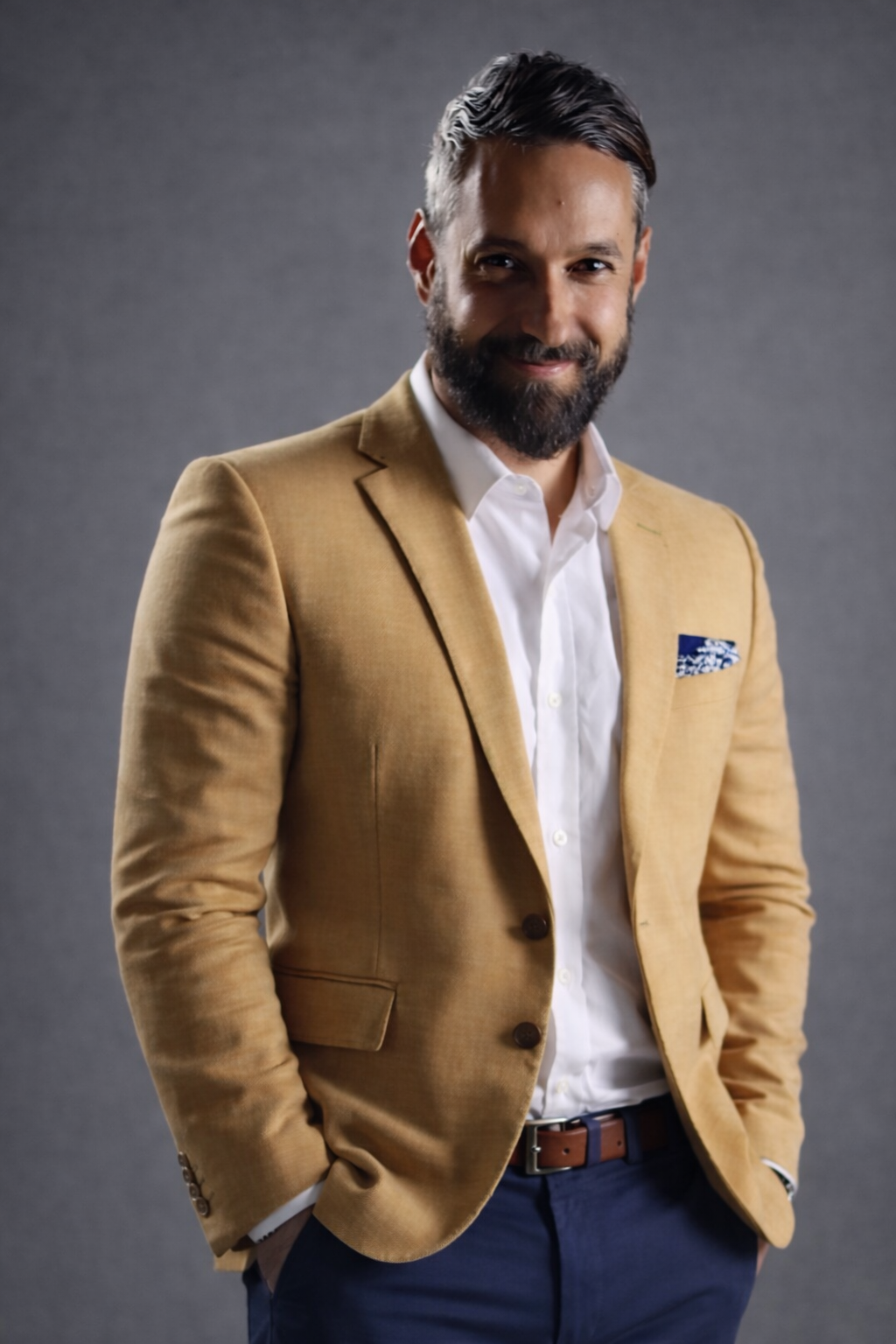 A tech leader and expert with dark hair, a beard, and a light skin tone, wearing a light gray blazer and white shirt, smiling at the camera against a neutral background.