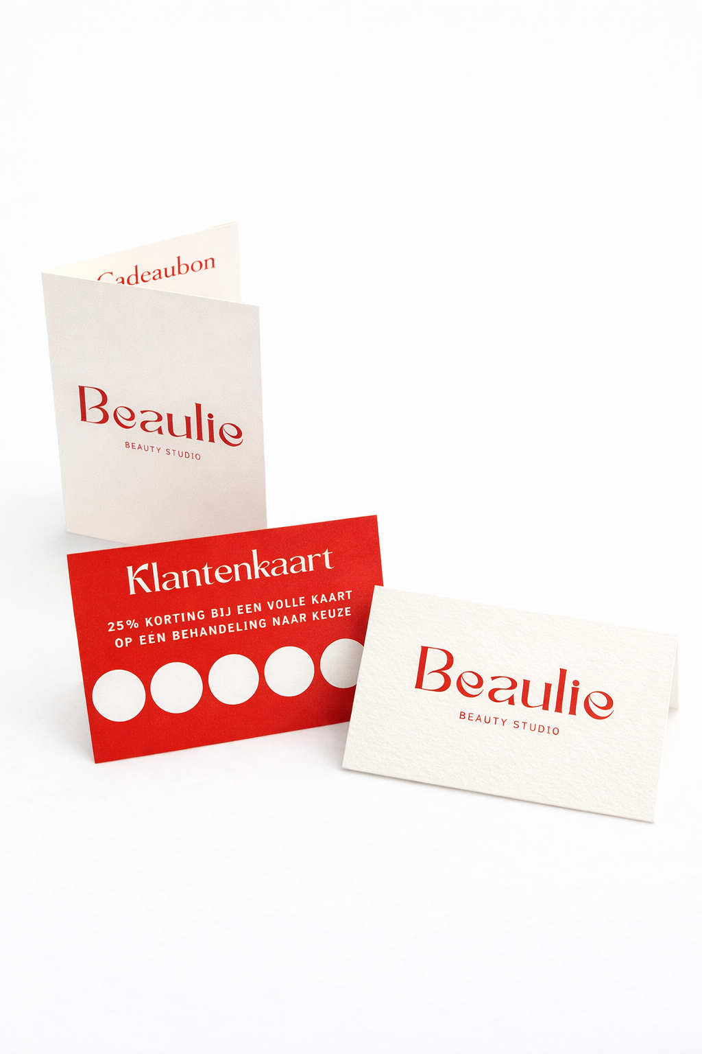 een visitekaartje van Beautie Beauty Studio, een rode klantenkaart met 25% korting, en een cadeaubon met dezelfde branding.