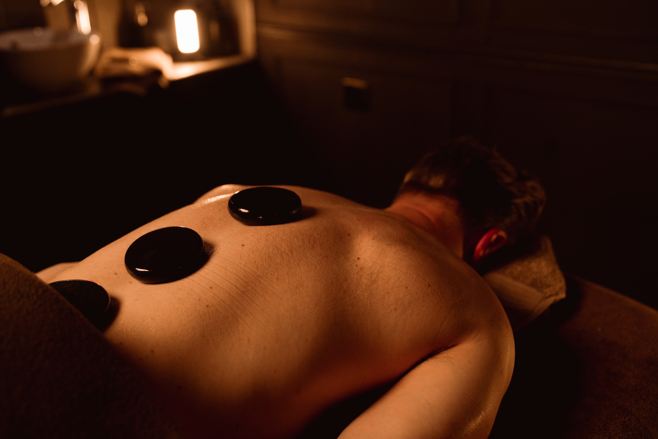 Person receiving a massage with a hand pressing on their back in a softly lit room