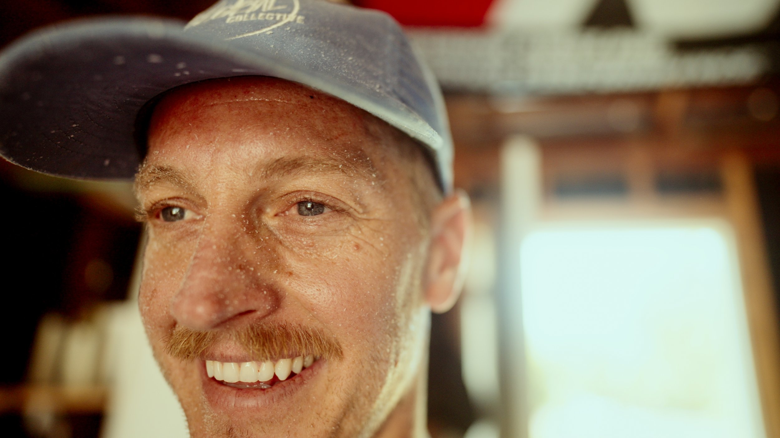 Close-up of a smiling man wearing a baseball cap.