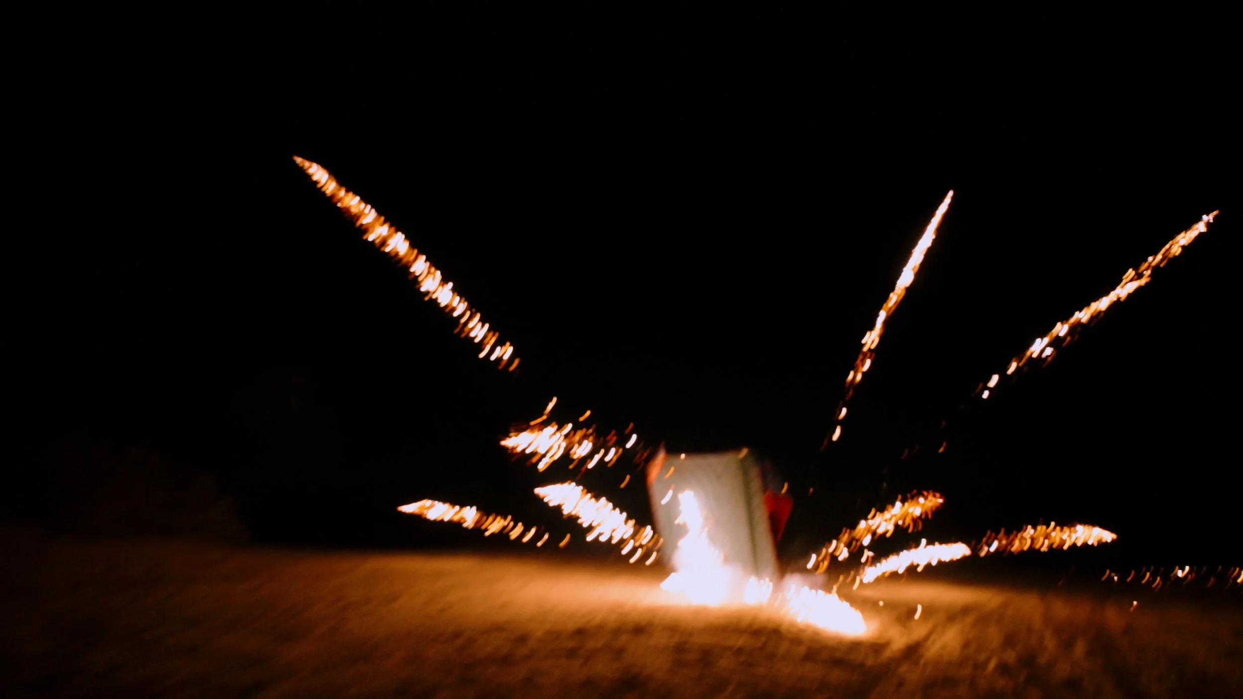 A firework exploding in the night sky with bright sparks and trails.