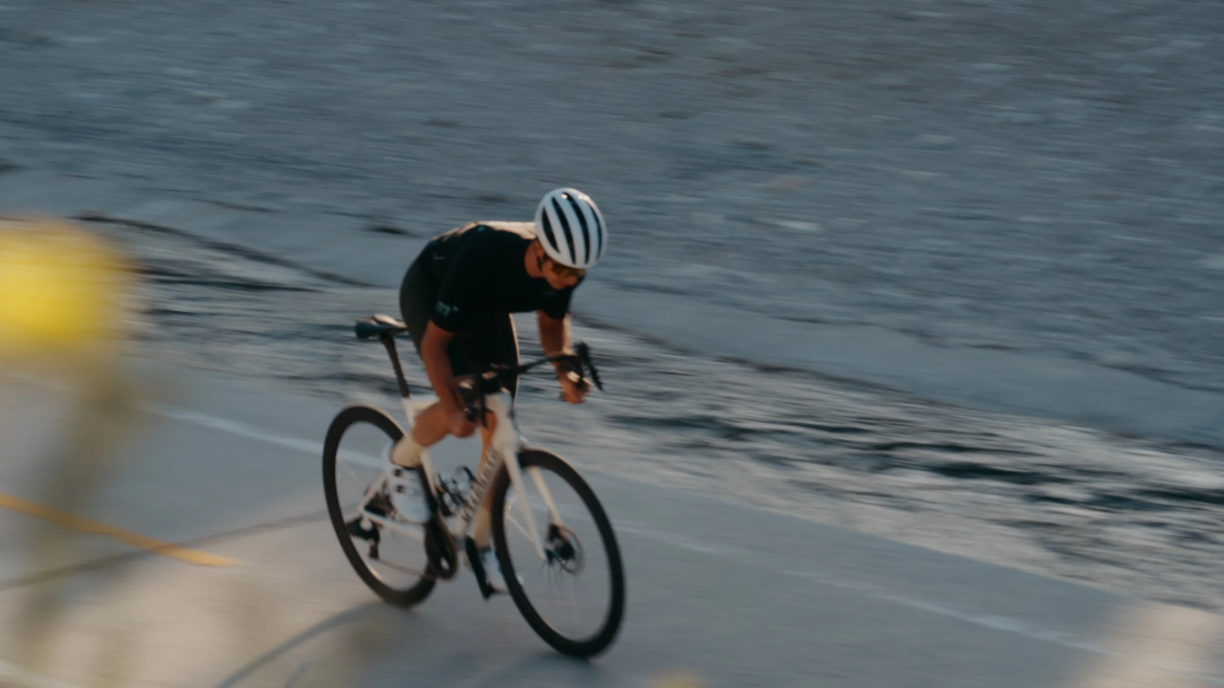 A person riding a bicycle quickly along the beach with ocean waves in the background.