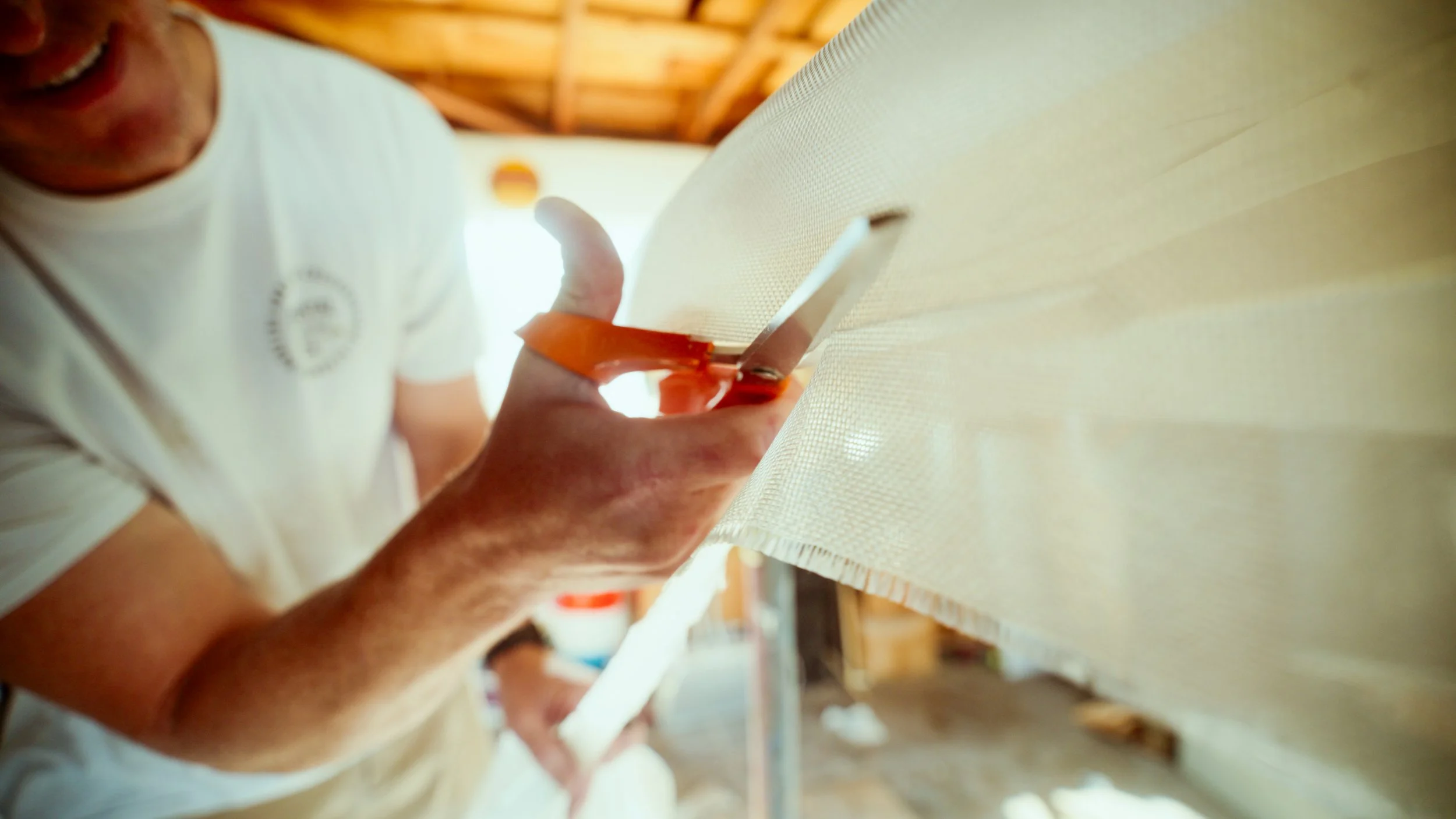 Person using scissors to trim a piece of fabric or mesh in a workshop setting.