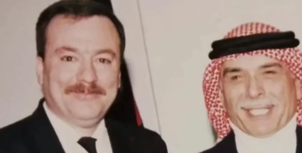 Two men posing for a photo, one with a mustache and the other wearing a keffiyeh.