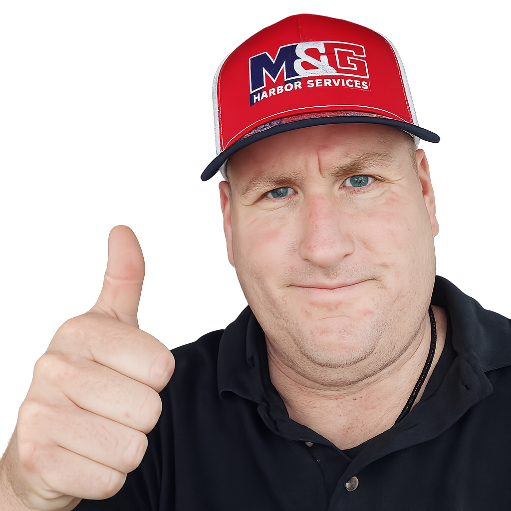 A man with blue eyes giving a thumbs-up gesture, wearing a red cap with the logo 'M&G Harbor Services' and a black shirt.