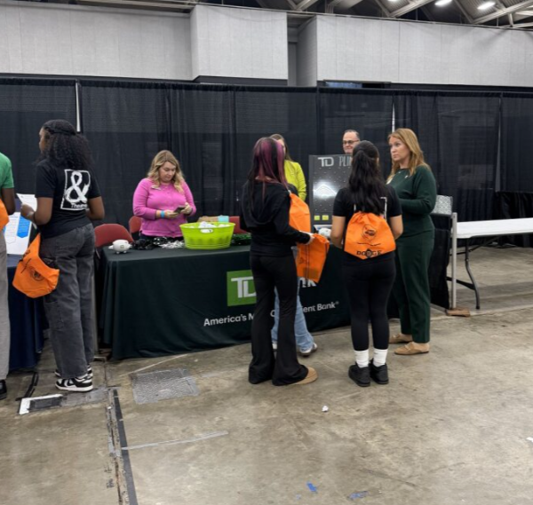 People standing and talking at a TD Bank booth at an indoor event or convention.