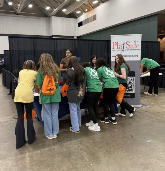 Group of young girls gathered around a table at a wellness event, with a PlaySafe banner in the background.