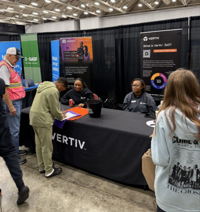 People at a Vertiv booth at a conference or tradeshow, with banners and signage, including one explaining Vertiv 360.