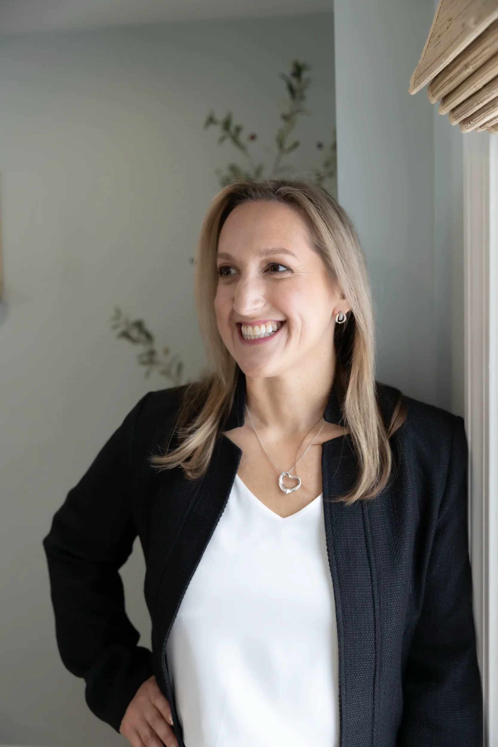 Tina is leaning on the wall, looking off to the right and smiling.