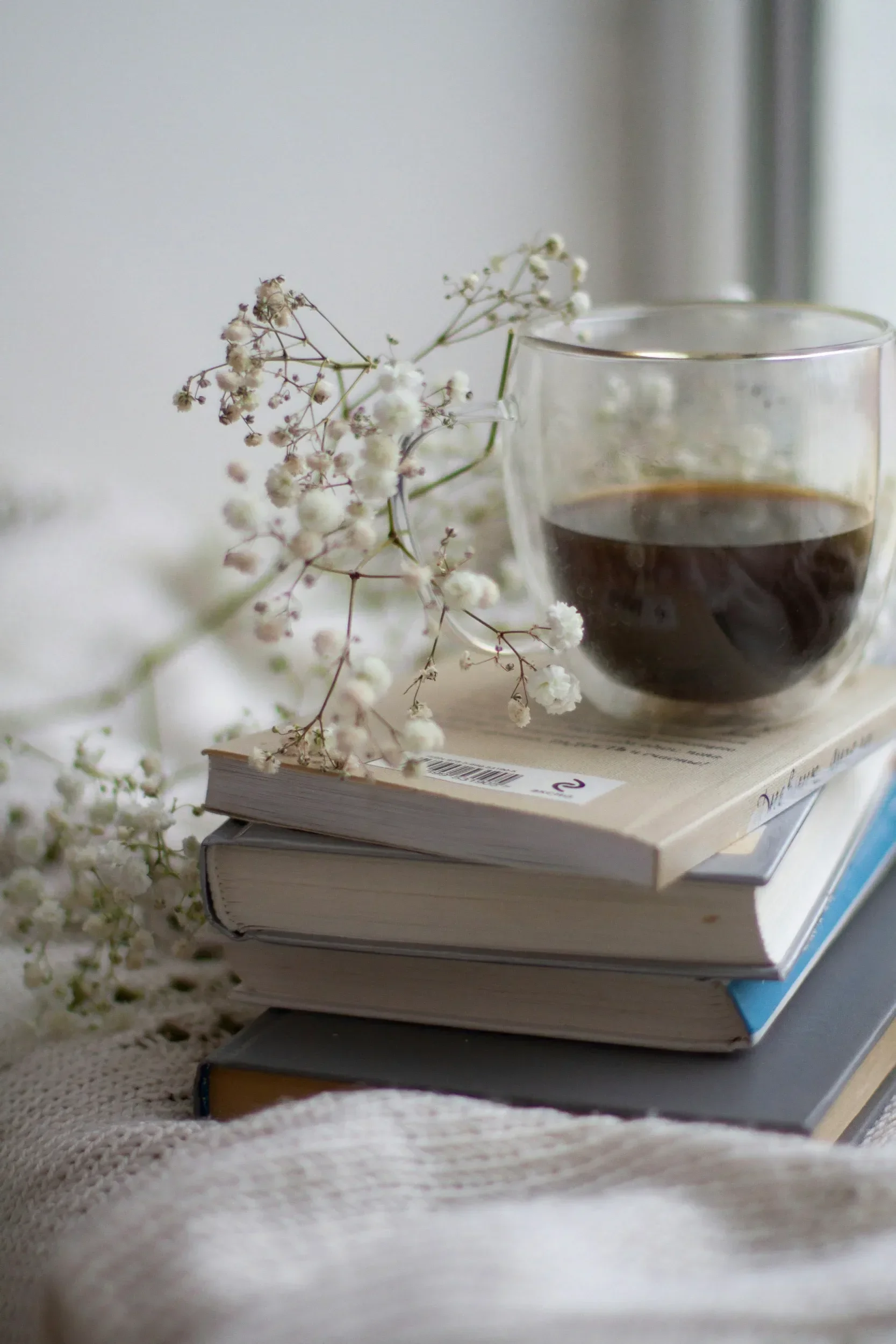 A stack of books on a desk with a clock on top