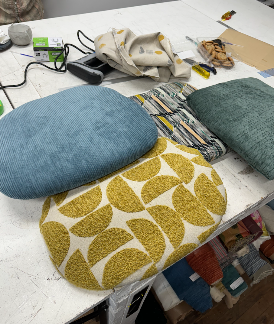 Multi-patterned dining room seats, including blue, yellow patterned, and green fabrics, with tools and other items scattered around.
