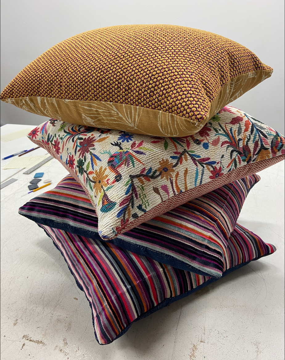 A stack of four decorative pillows with various patterns on a white surface.
