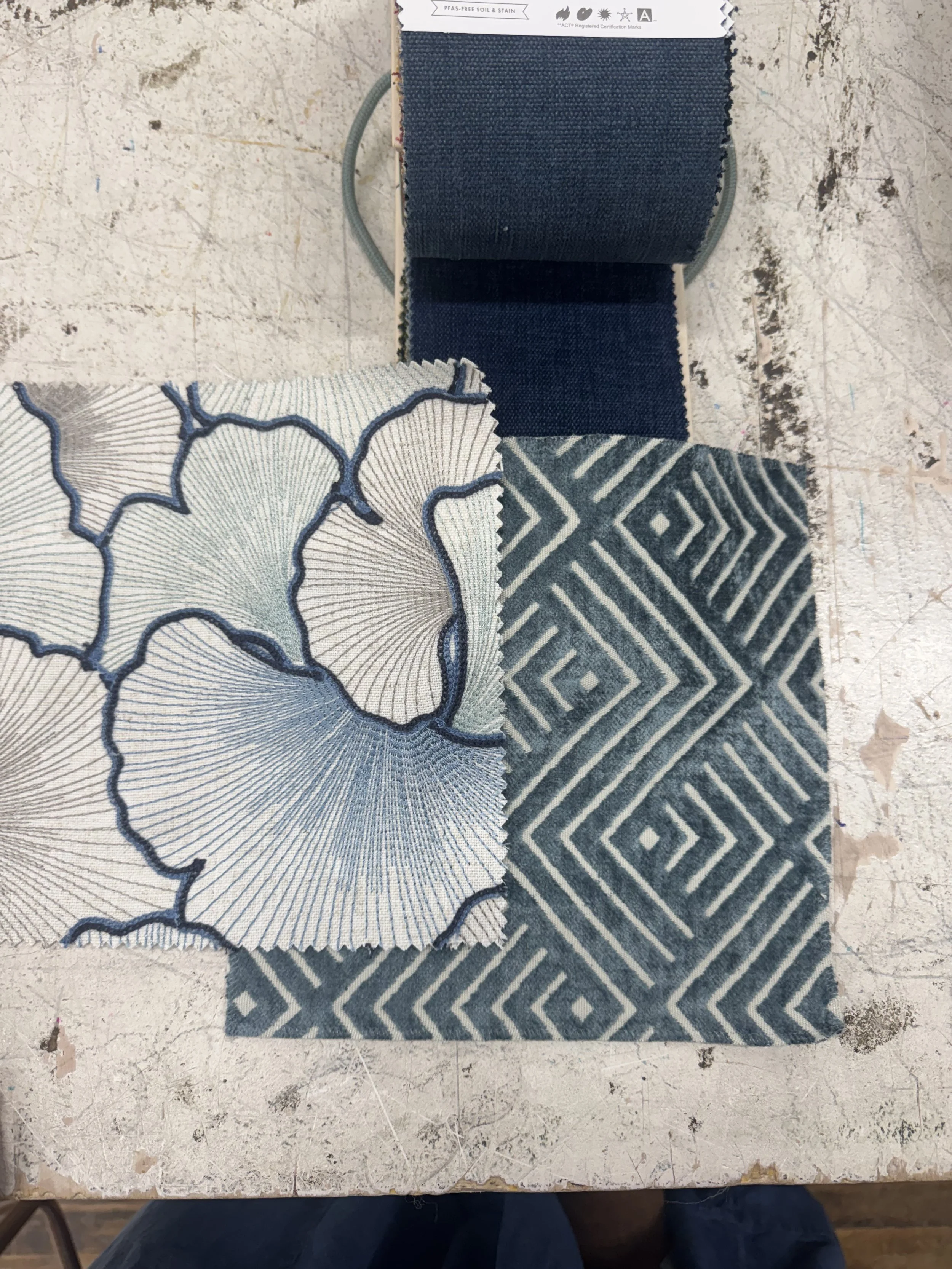 Patterned blue and white fabric swatches on a work table.