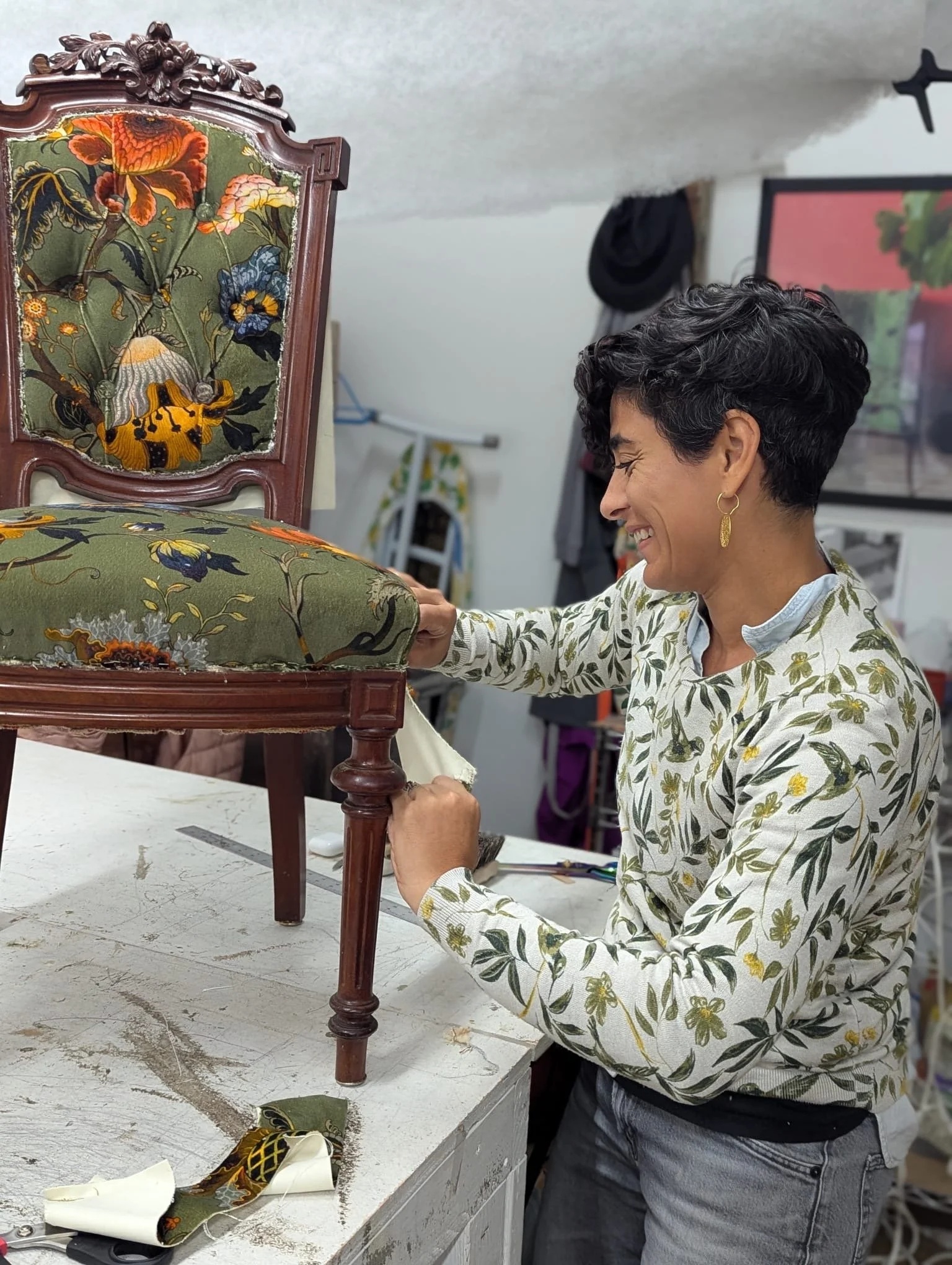 Ruti upholstering a vintage chair with embroidered floral fabric.