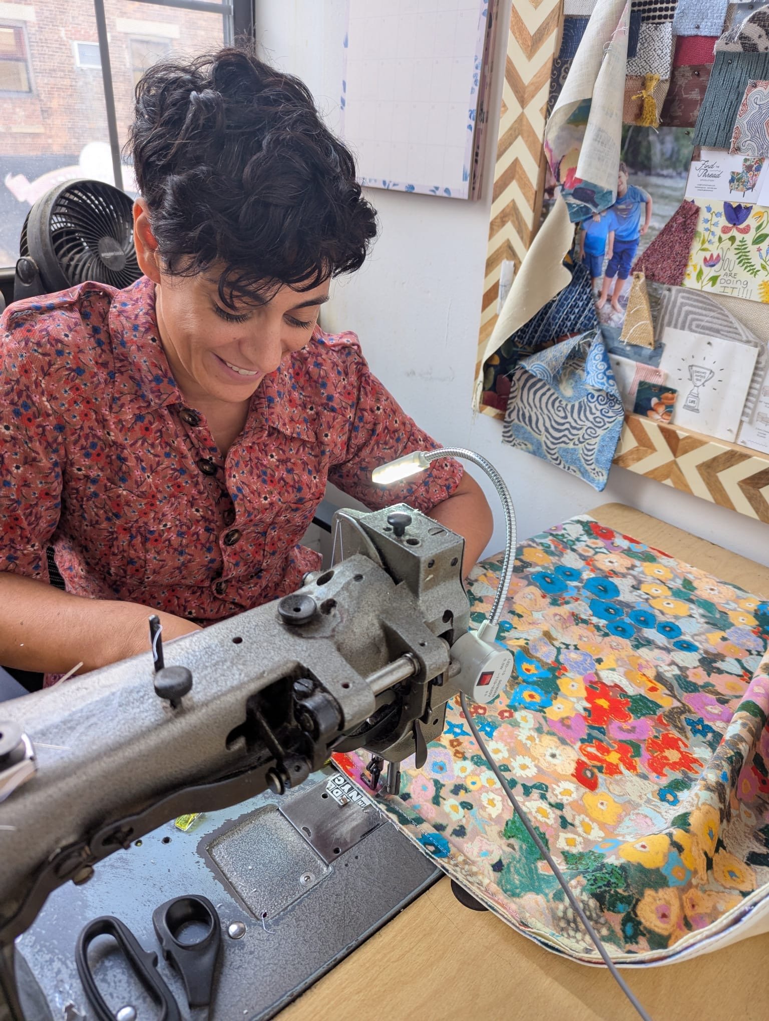 Ruti at her sewing machine with a bright floral fabric