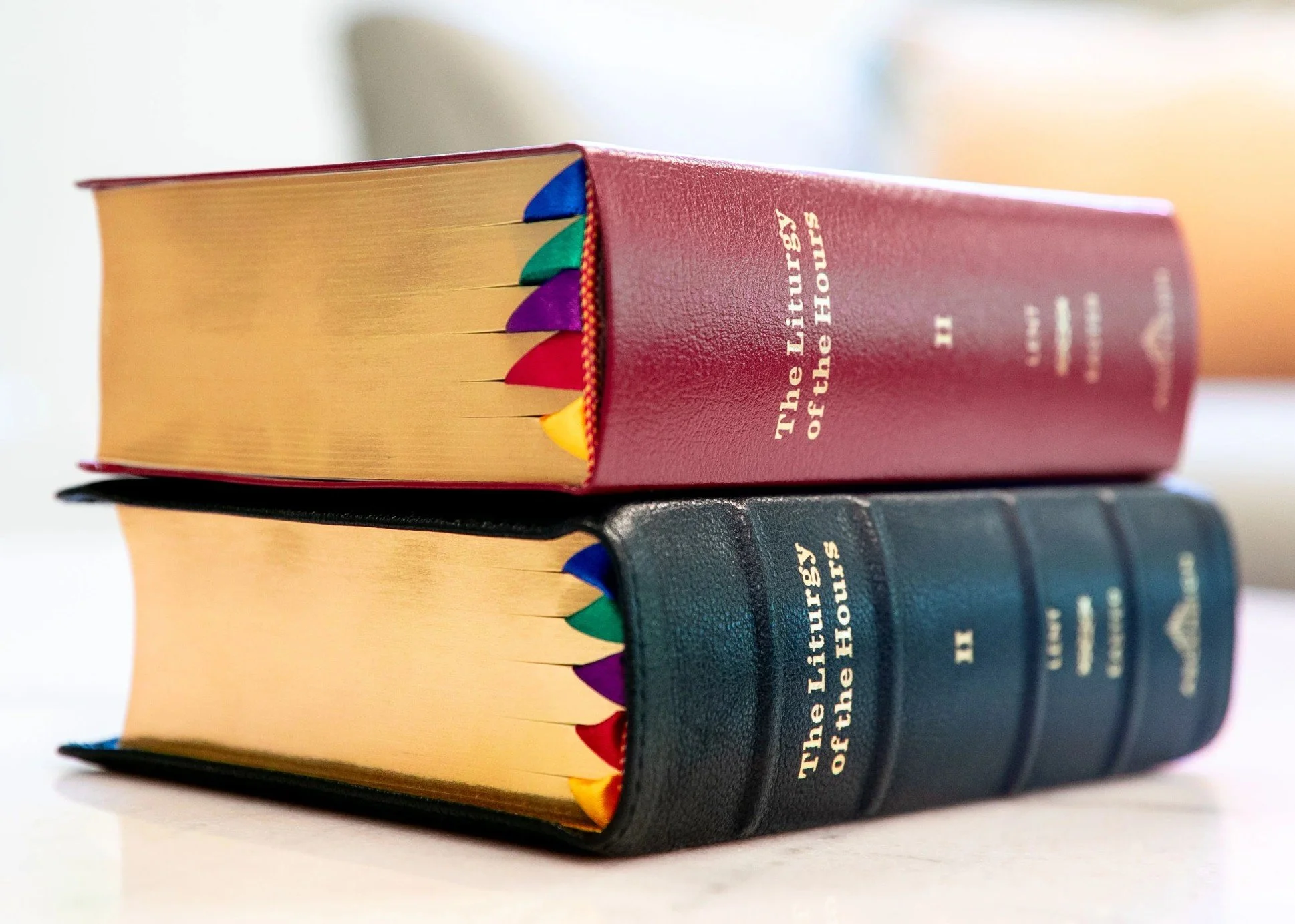Two religious hardcover books stacked horizontally, with the top book having multicolored bookmarks protruding from the pages.