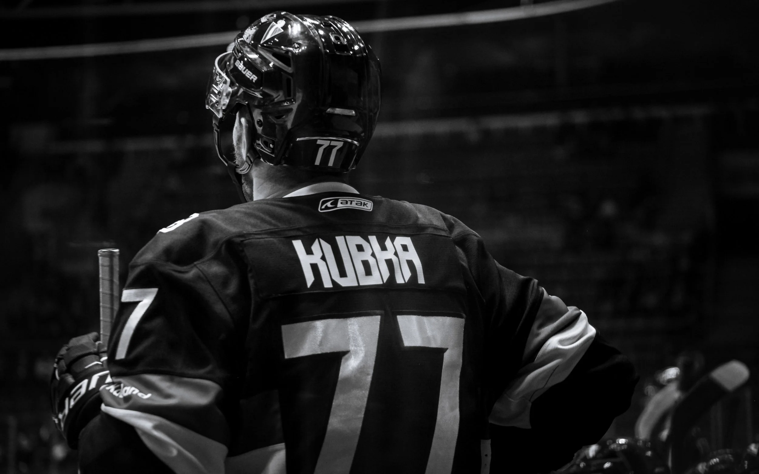 A hockey player wearing a helmet and a jersey with the name 'KURKA' on the back, seen from behind in black and white.