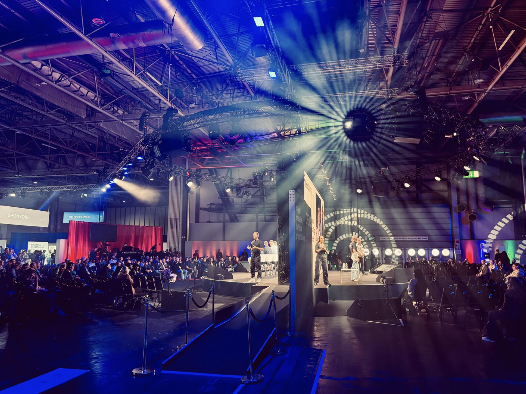 A large i conference or event with a stage, audience, and bright stage lights, including colorful spotlights and beams. Live show producer, set designer, table scaping, event producer, event consultant, freelance, private, corp, london worldwide ebay