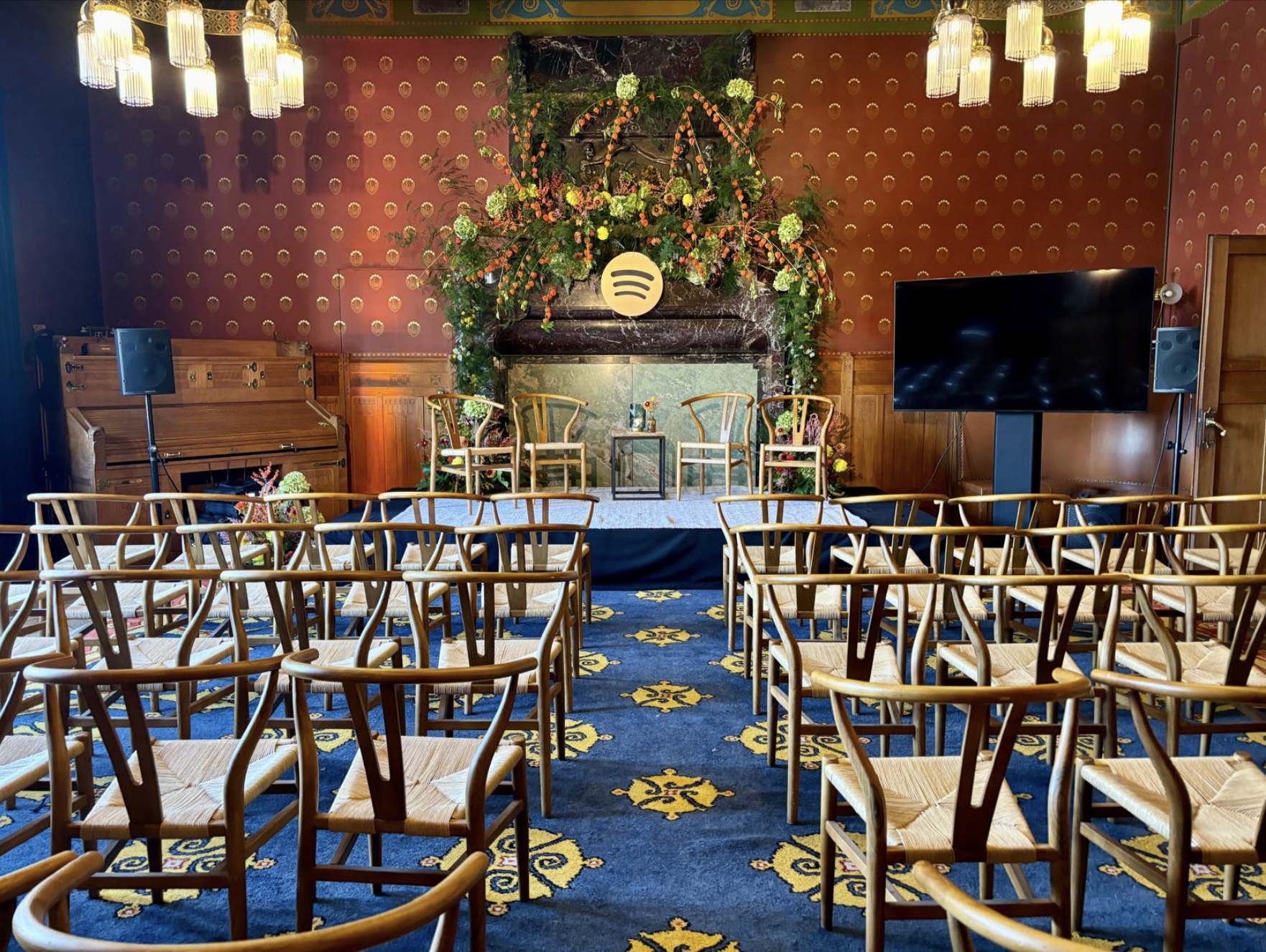 A decorated indoor space , floral arrangements, and a Spotify logo. The decor includes a fireplace with floral arrangements and colorful lighting. Live show producer, set designer, table scaping, event producer, event consultant, freelance, private,