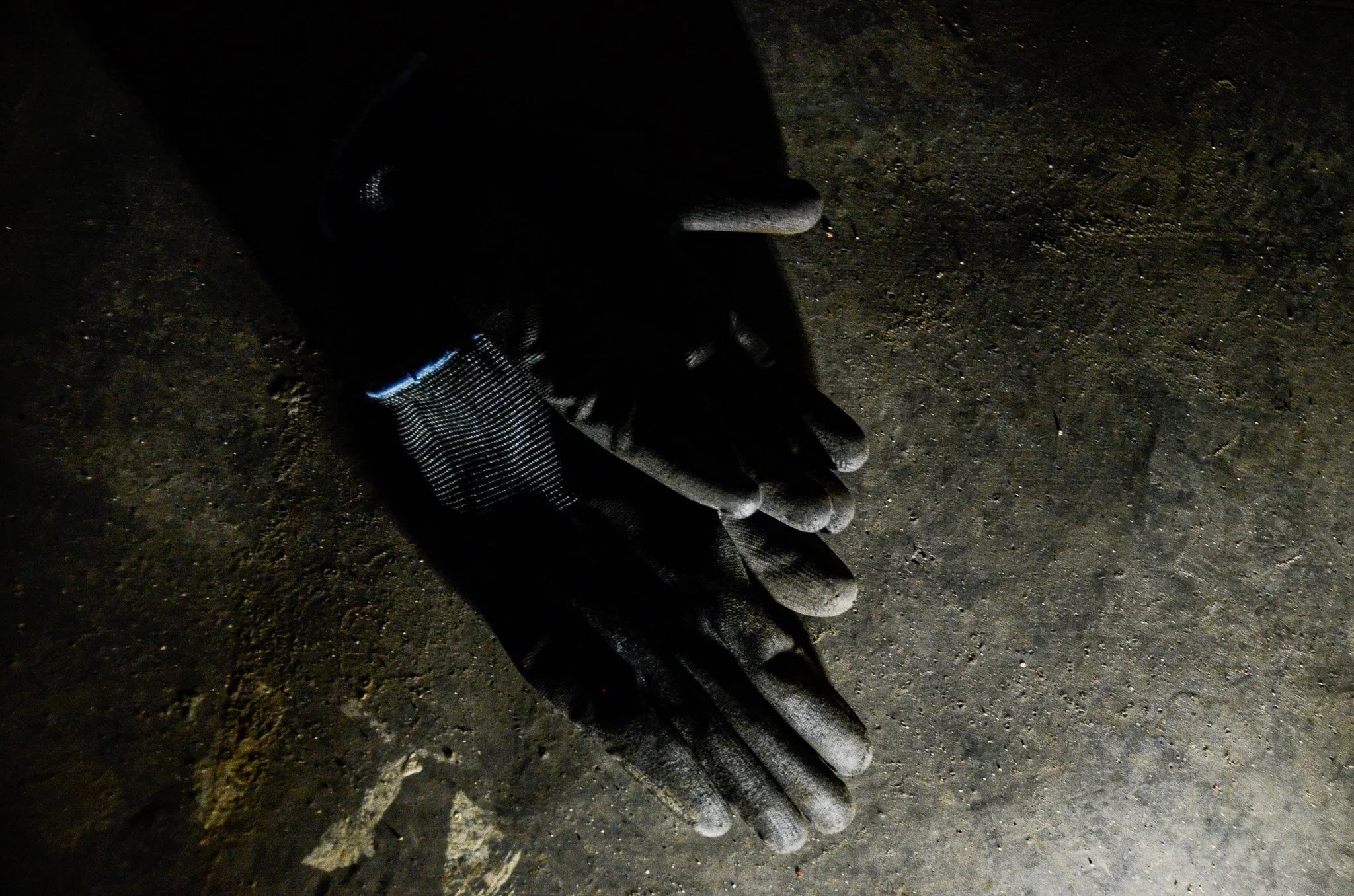 A black glove on a dark surface with a staggered, layered appearance.