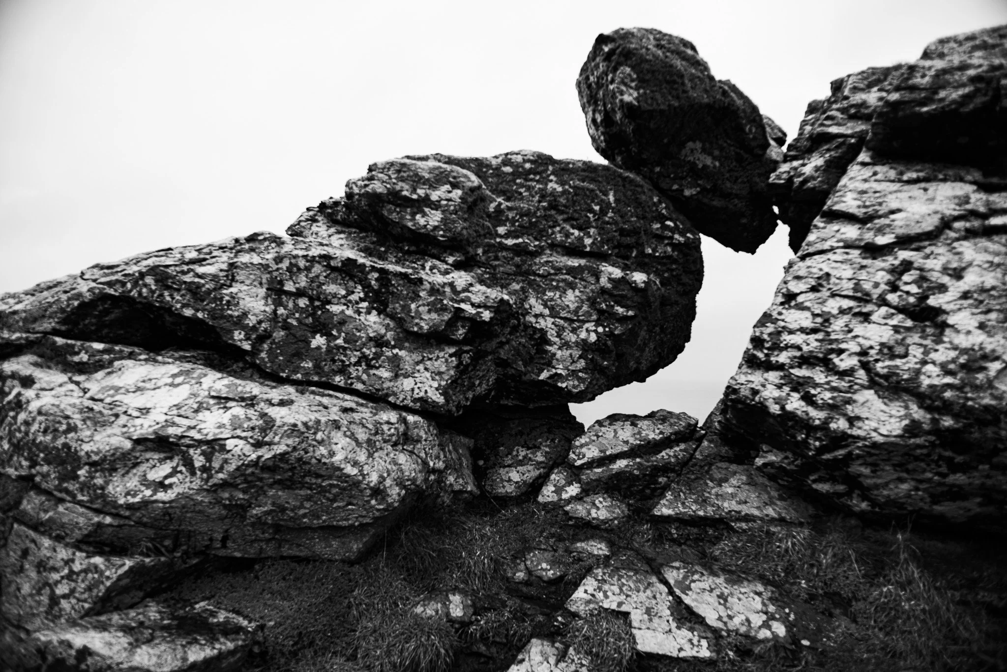 Black and white photograph of large, textured rocks stacked on a hillside.