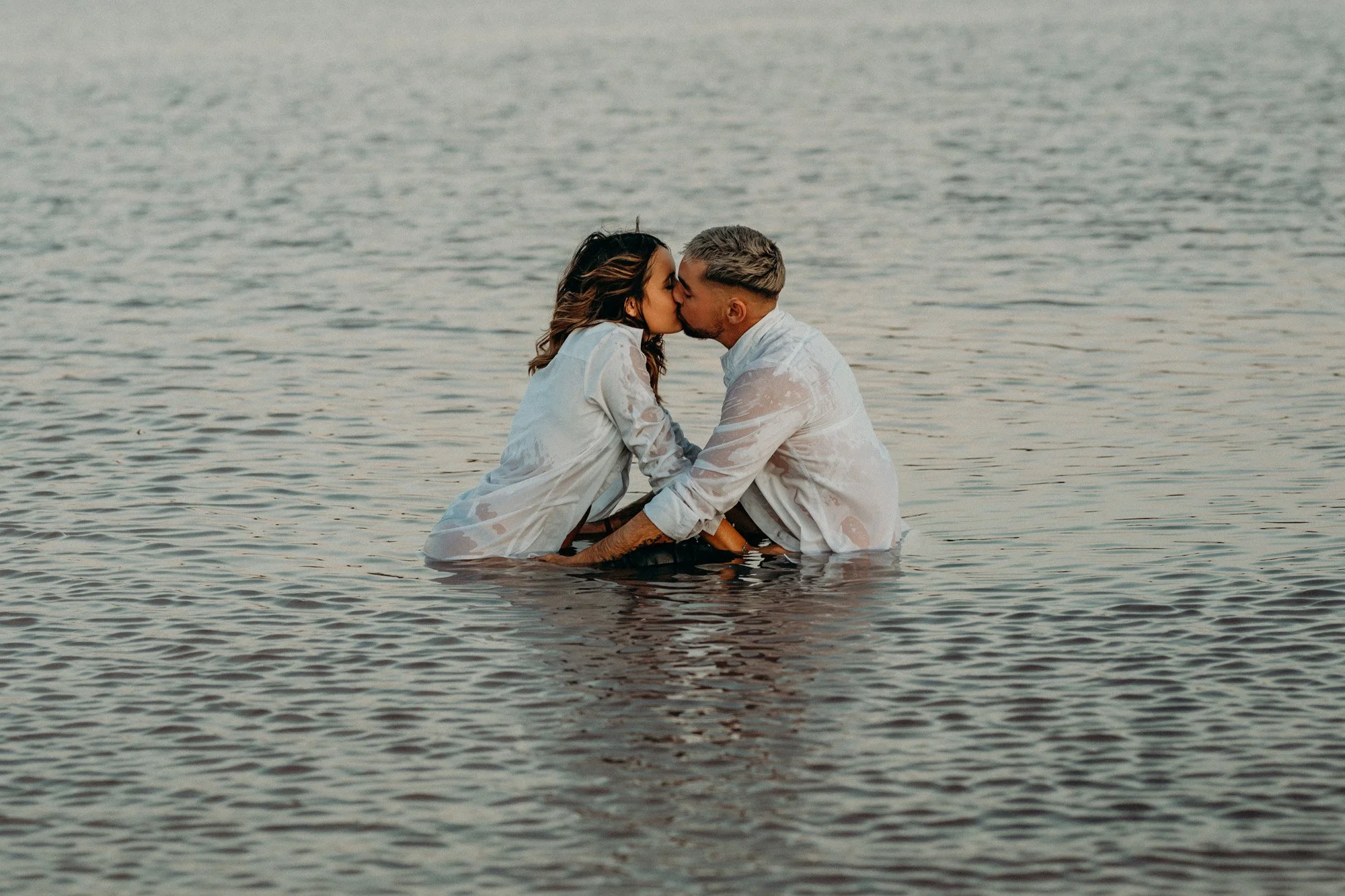 couple s'embrassant dans l'eau au coucher du soleil