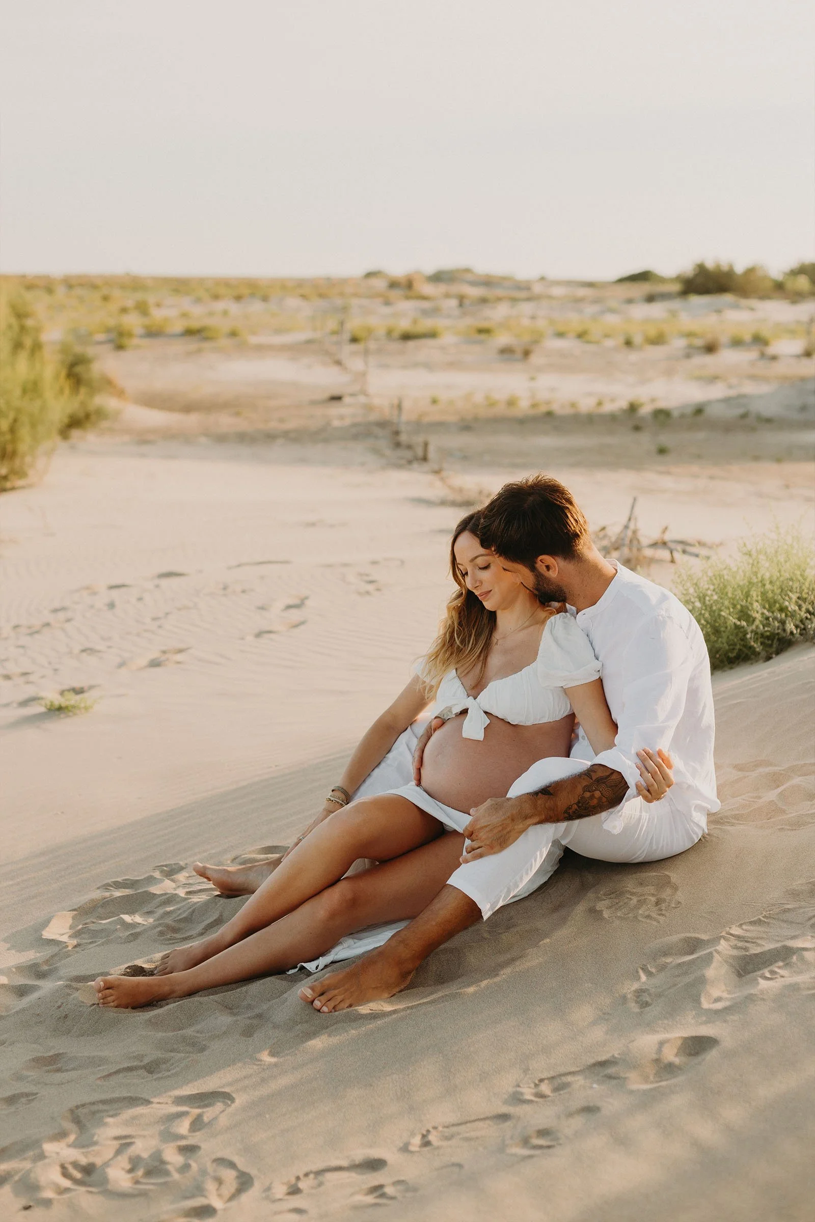 séance photo grossesse en couple assis dans le sable des dunes de Camargue