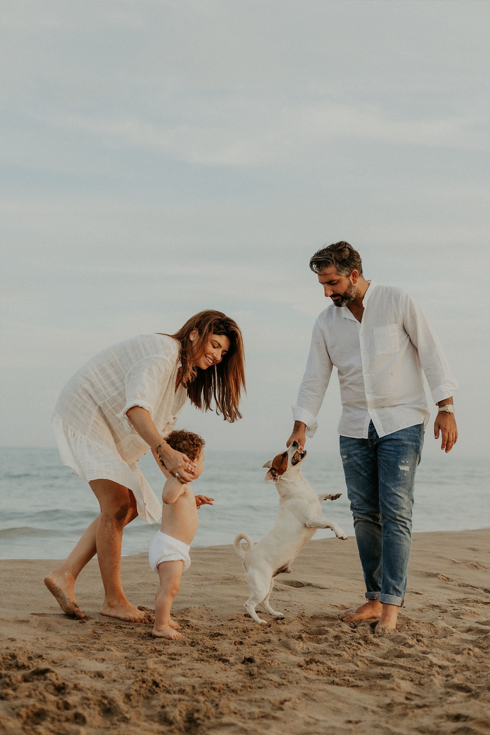 famille de trois personnes et leur chien jouent sur la plage au coucher du soleil en Camargue
