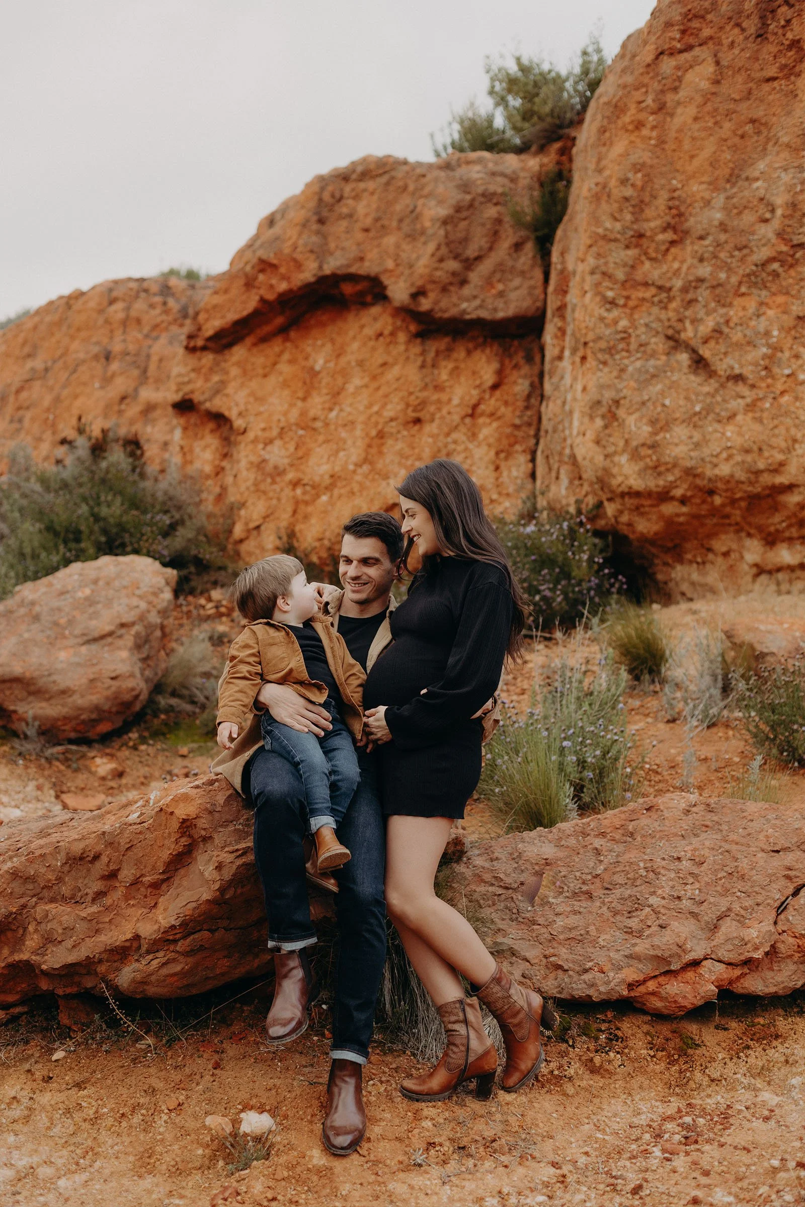 un couple et un enfant posent dans un paysage de roche rouge en Provence