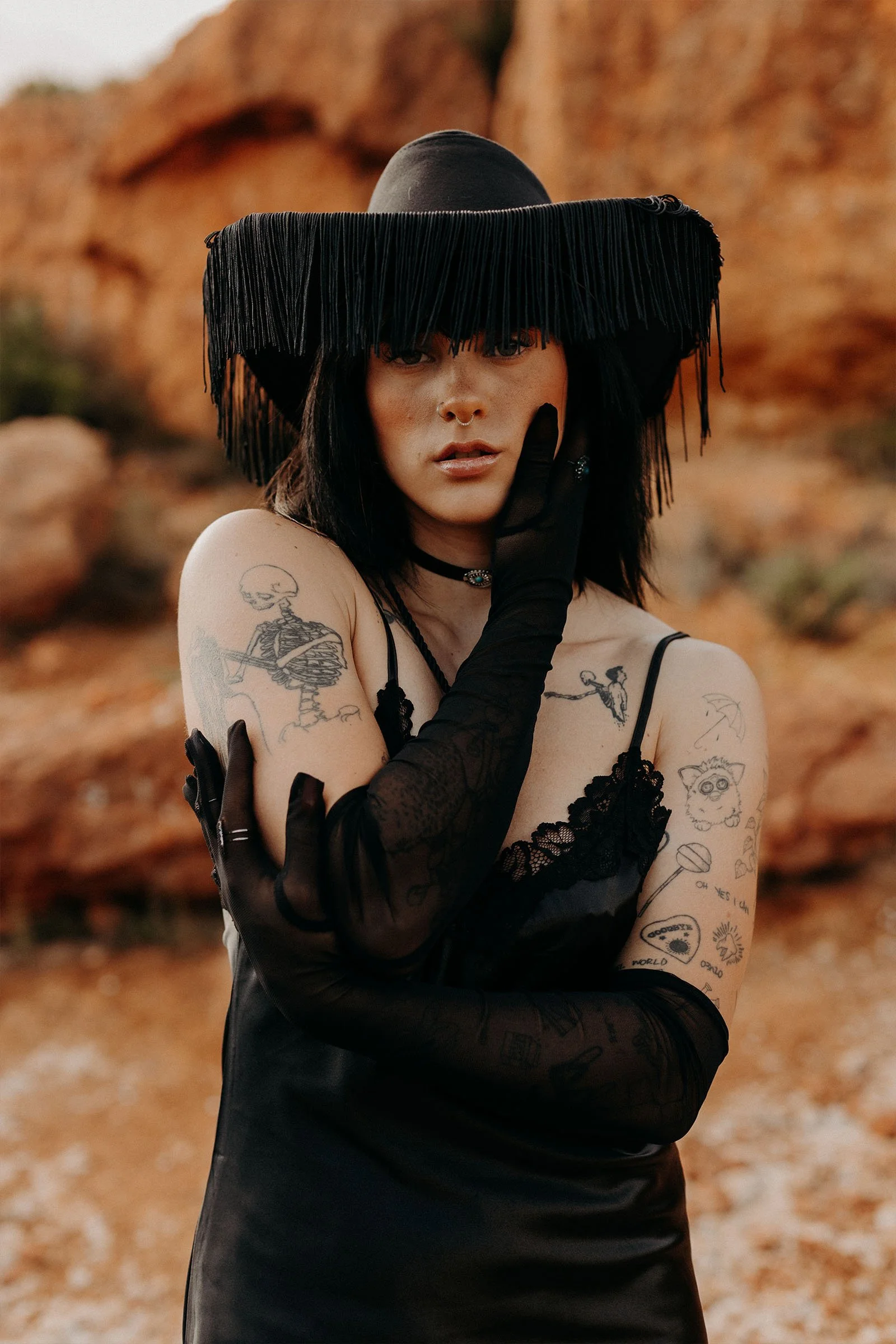 portrait femme avec un chapeau noir à franges avec les montagnes ocres en arrière plan