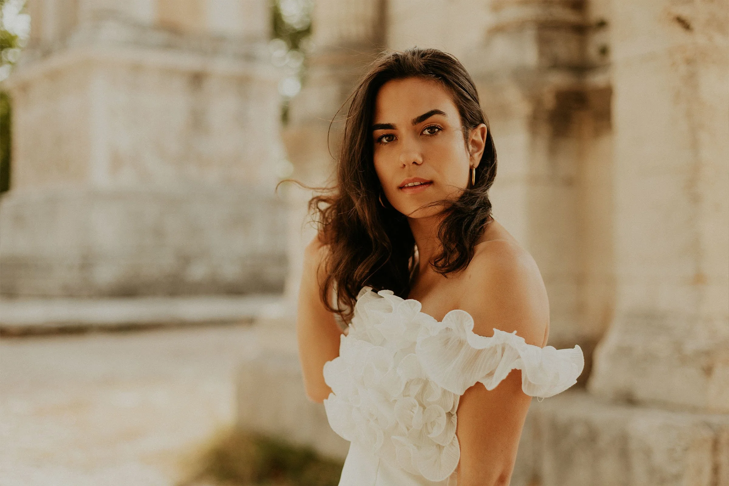 femme en robe blanche posant devant le site archéologique de Glanum à Saint-Rémy-de-Provence