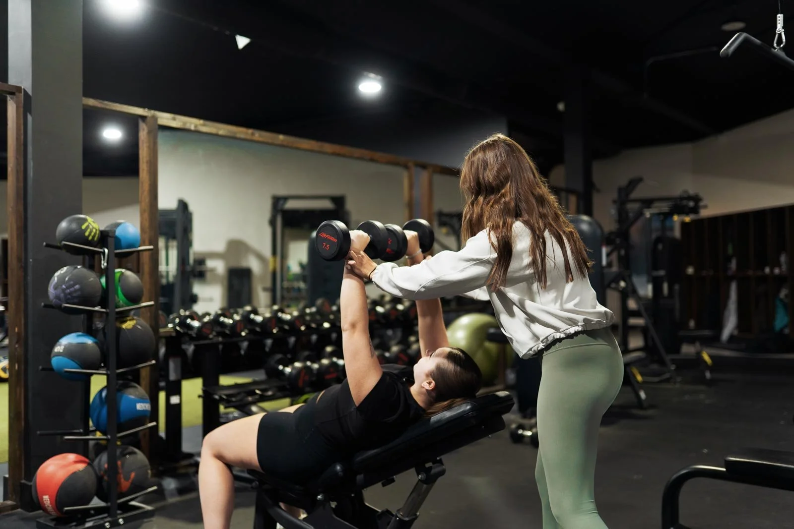 London personal trainer, Ella Vrbanac helping her clients form on incline dumbbell press
