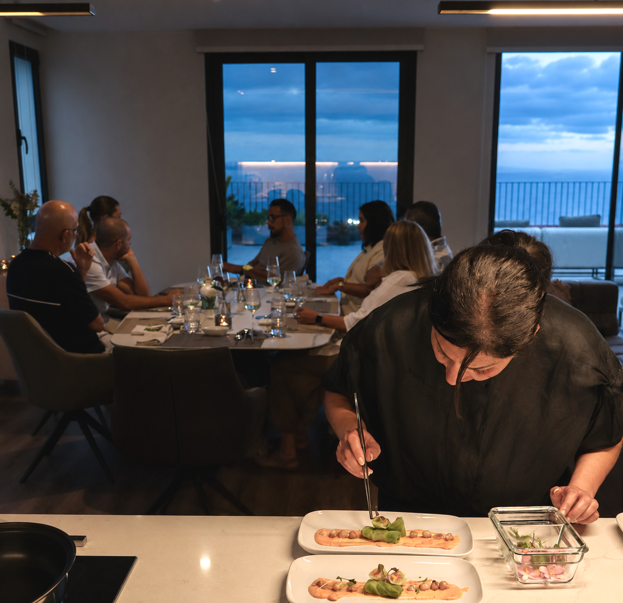 Host Simin plating a course while guests enjoy a private dining experience at Food with a View in Madeira.