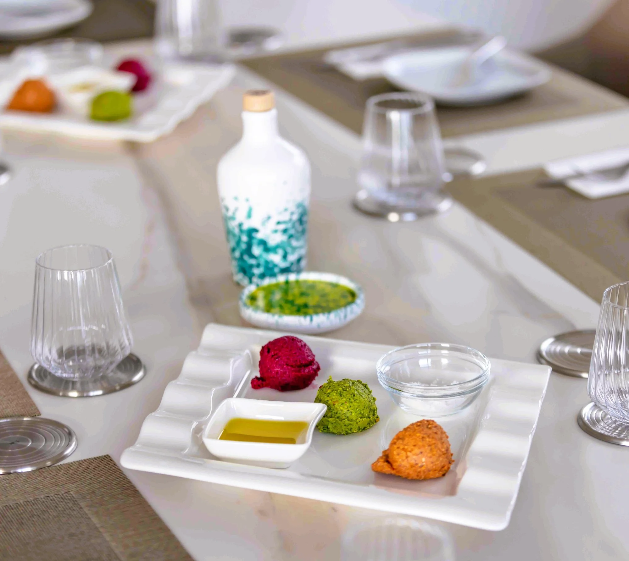 Vegetarian starter with three bites served alongside olives in a porcelain bowl.