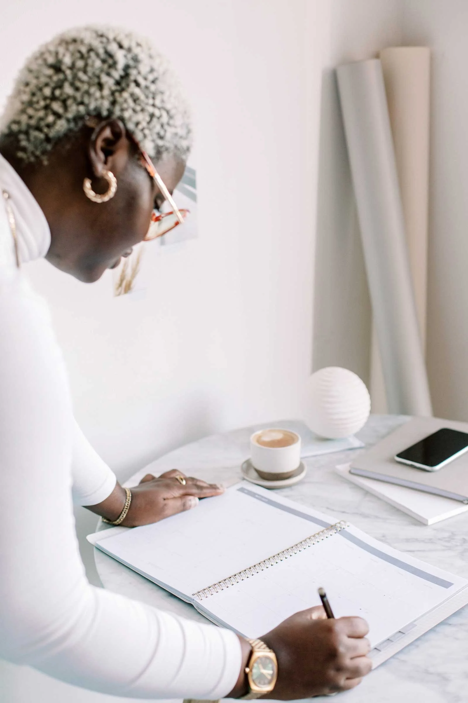 Maker writing in a notebook at a desk while developing a creative business